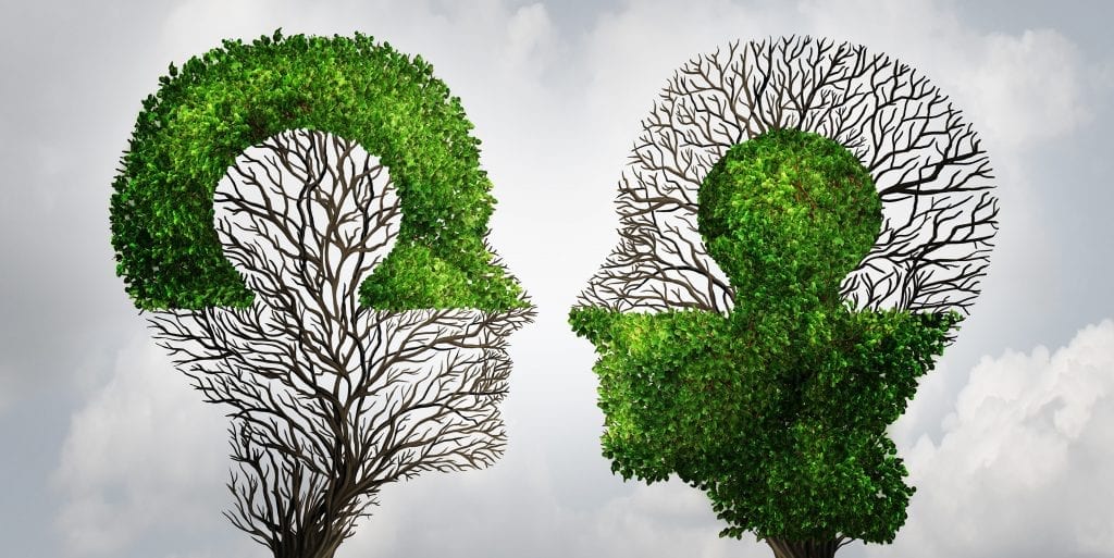 Perfect business partnership as a connecting puzzle shaped as two trees in the form of human heads connecting together to complete each other as a corporate success metaphor for cooperation and agreement as equal partners.