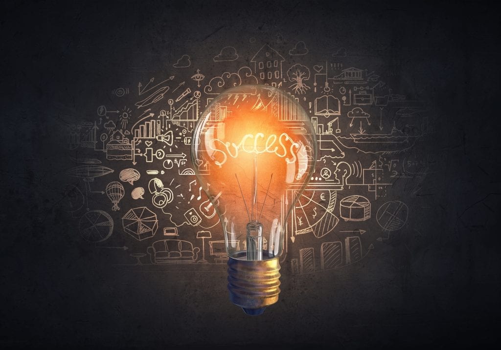 Glowing glass light bulb and business sketches at dark background