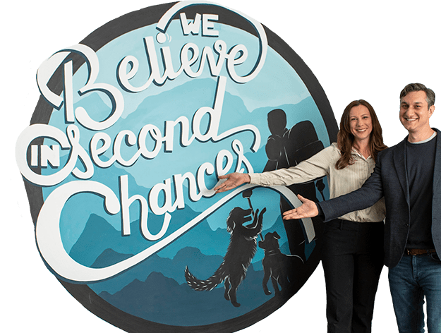 two professionals beside a mural reading "We believe in second chances"