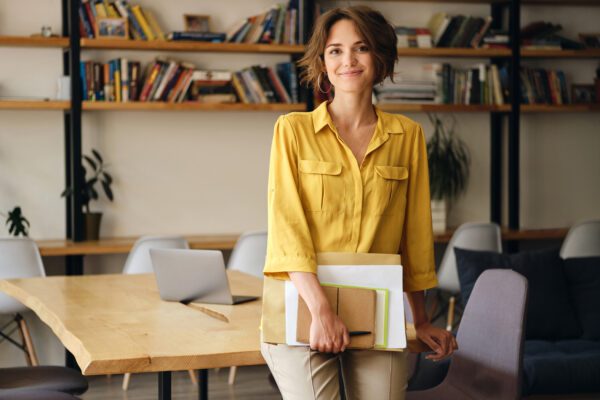 A self-employed woman in a yellow shirt in a home office