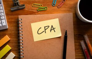 A notebook on a desk with a post-it note that says "CPA" on it.