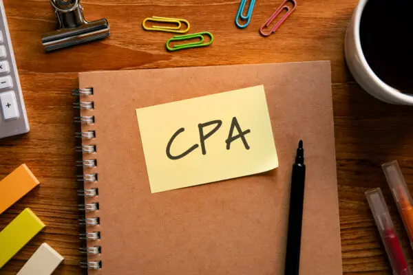 A notebook on a desk with a post-it note that says "CPA" on it.